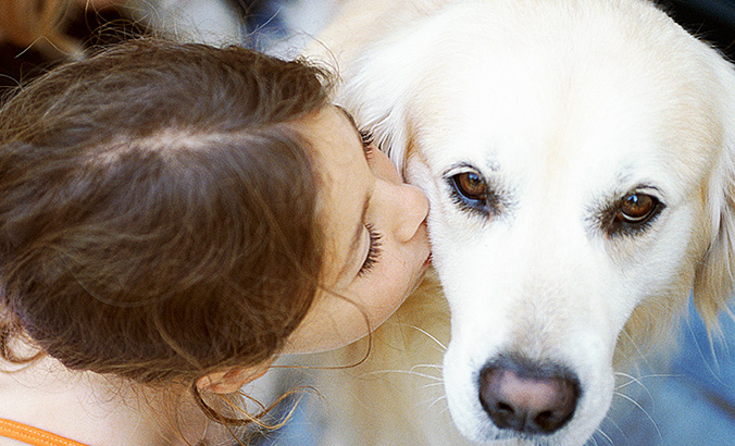 Mädchen küsst einen Hund ins Fell