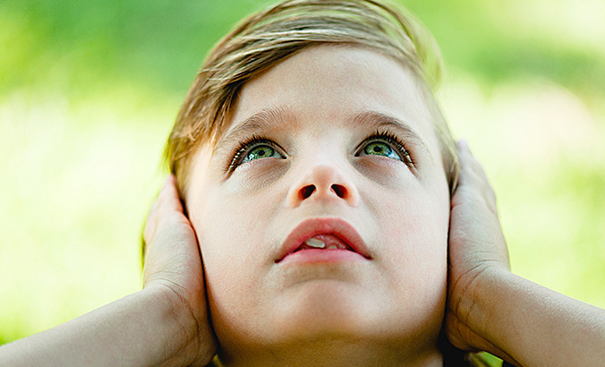 Kind hält sich die Ohren zu