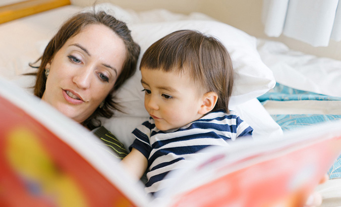 Mutter schaut mit ihrem Kind ein Bilderbuch an