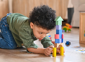 Kind spielt mit Bauklötzen und baut einen Turm.