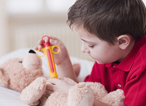 Kind spritzt seinen Teddy mit einer Spielzeugspritze
