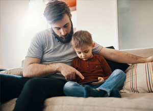 Vater schaut gemeinsam mit Sohn auf Smartphone