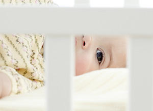 Baby schaut durch Gitterbett