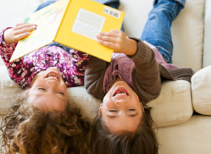 Mädchen lesen gemeinsam kopfüber ein Buch