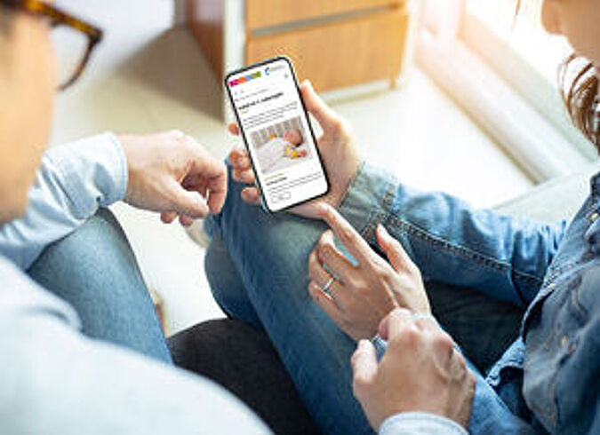 Ein Elternpaar liest gemeinsam den Newsletter von Kindergesundheit-info.de auf dem Smartphone.