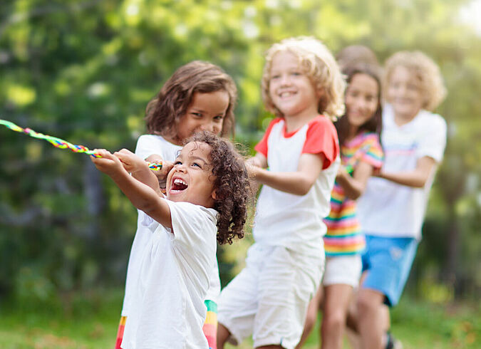 Ein paar Kinder spielen amüsiert Tauziehen im Freien.