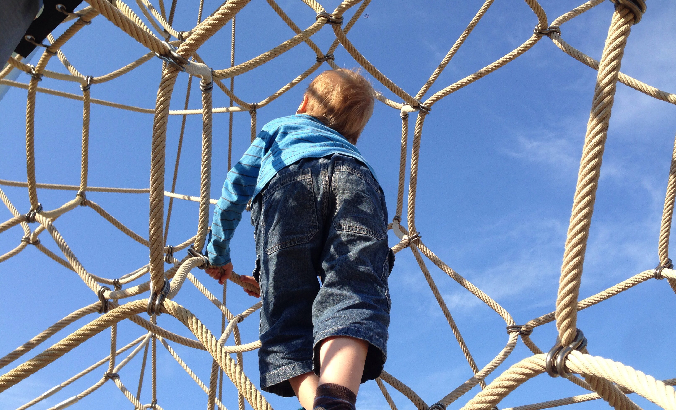 Kind klettert ein Klettergerüst empor