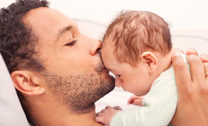 Vater küsst seinem Baby sanft auf die Stirn