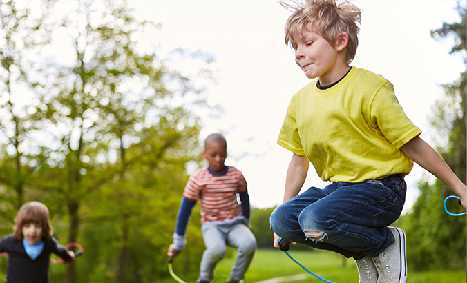 Kinder spielen draußen mit Springseil