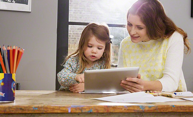 Mutter und Kind sitzen an Tabletcomputer