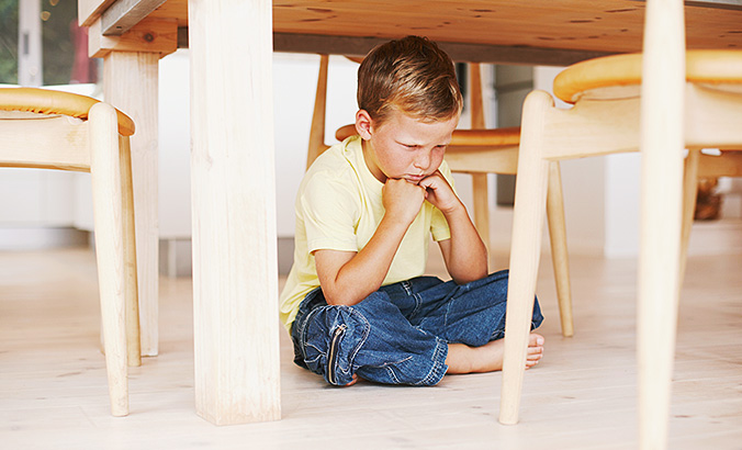 Wütendes Kind sitzt unter Tisch
