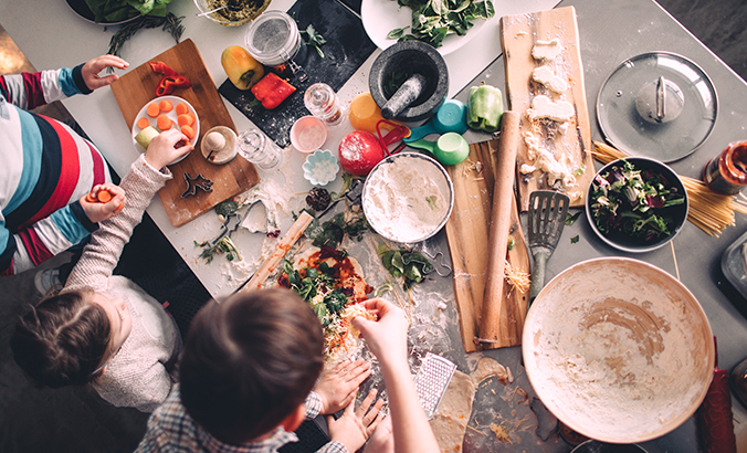 Kinder belegen selber eine Pizza mit frischen Zutaten