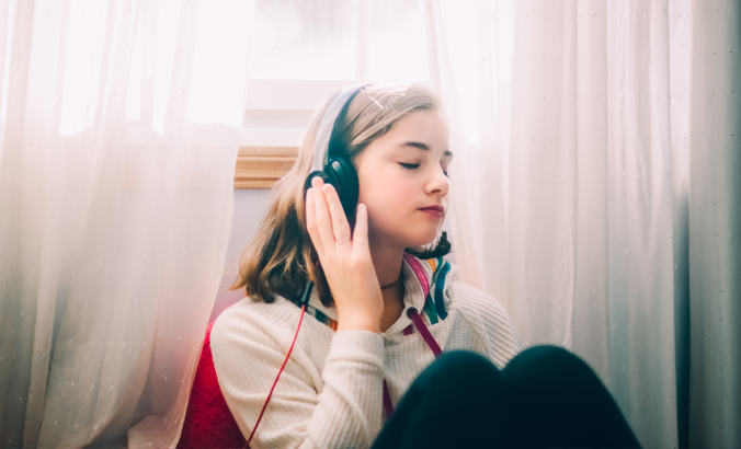 Weiblicher Teenager hört im Zimmer Musik über Kopfhörer