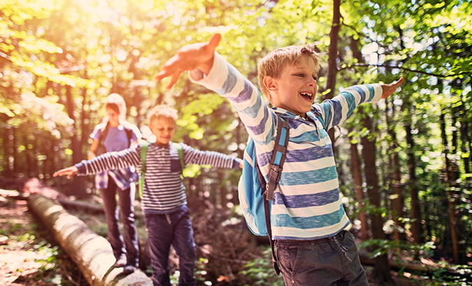 Kinder balancieren in der Natur auf einem Baumstamm