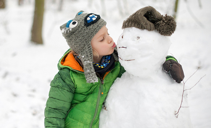 Kind umarmt einen Schneemann