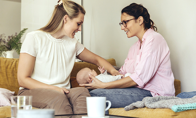 Zwei Frauen mit Neugeborenem im Gespräch