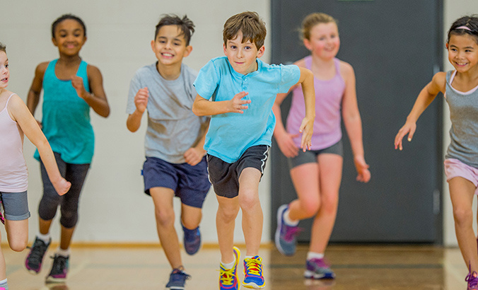 Mädchen und Jungen rennen in Sporthalle