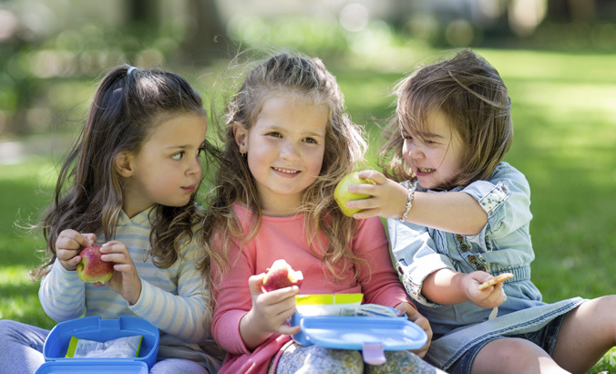 Drei Kleinkinder beim Picknick im Garten