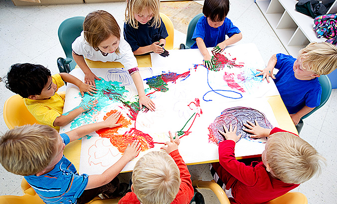 Eine Gruppe Kinder malt mit Fingerfarben an einem Tisch
