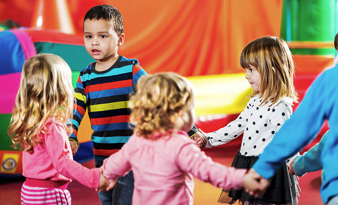 Kinder halten sich an den Händen und laufen im Kreis 