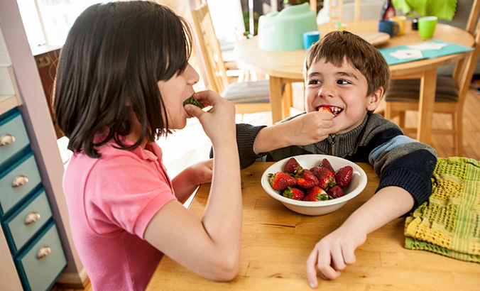 Zwei Kinder essen Erdbeeren