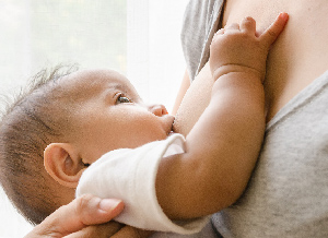 Ein Baby saugt an der Brust seiner Mutter und trinkt Muttermilch.