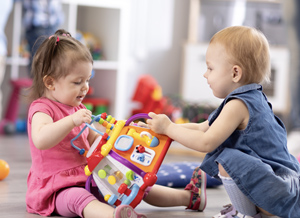 Zwei Kinder spielen gemeinsam auf dem Boden