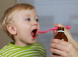 Kind öffnet den Mund für ein Löffel Medizin