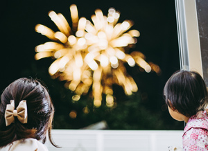 Kinder beobachten ein Feuerwerk aus dem Fenster