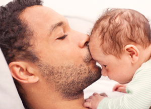 Vater gibt Neugeborenem einen Kuss auf die Stirn