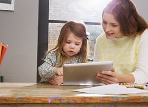 Frau sitzt mit Kind vor Tablet PC