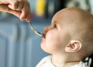 Baby wird mit Löffel gefüttert.