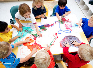 Eine Gruppe Kinder malt mit Fingerfarben an einem Tisch