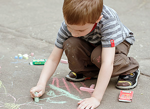 Junge malt mit Kreide auf dem Asphalt