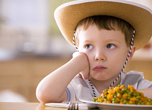 Junge sitzt vor Teller mit Gemüse