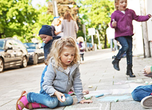 Kinder spielen draußen auf dem Bürgersteig und malen mit Kreide