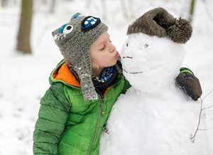 Kind umarmt einen Schneemann