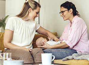 Zwei Frauen mit Neugeborenem im Gespräch