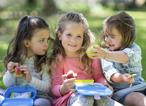 Drei Kleinkinder beim Picknick im Garten