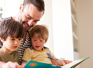 Vater schaut mit seinen Kindern ein Bilderbuch an