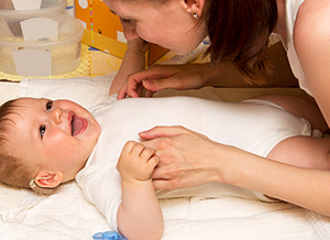 Baby liegt lachend auf Wickeltisch