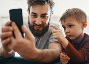 Vater schaut gemeinsam mit Sohn auf ein Smartphone