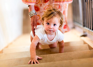 Mutter hilft Baby beim Treppe hochkrabbeln